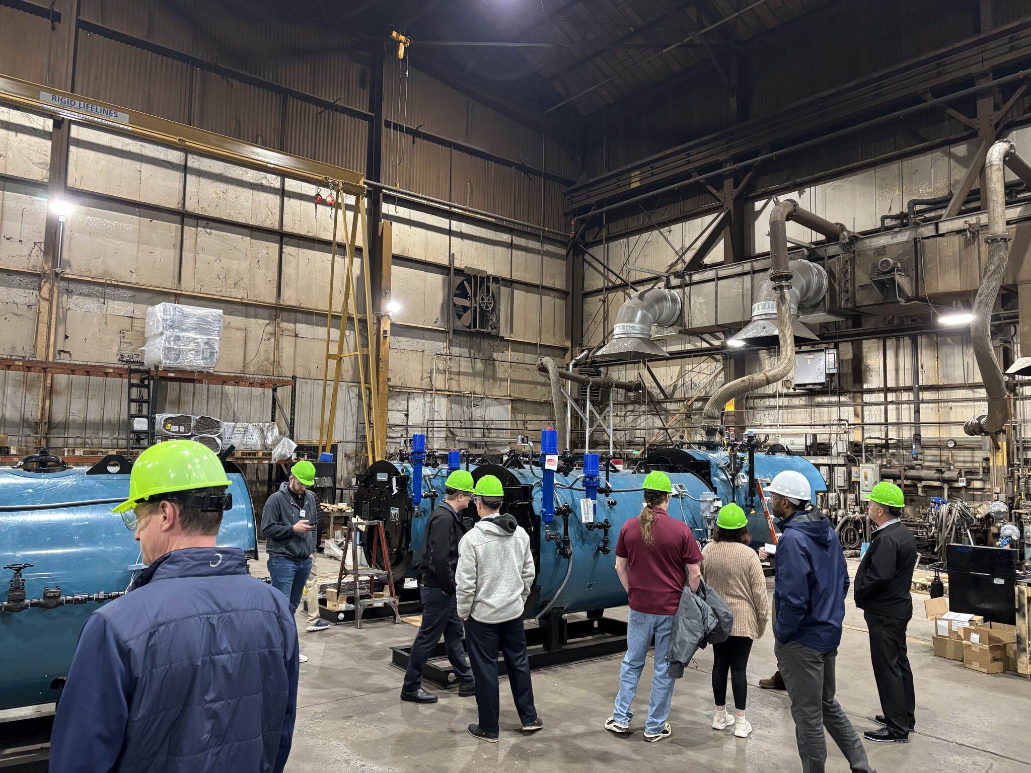 Group touring manufacturing facility with industrial equipment Group touring manufacturing facility with industrial equipment